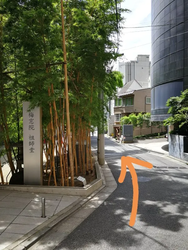 細道に入り左側に梅窓院が見える様子（オレンジ矢印付き）