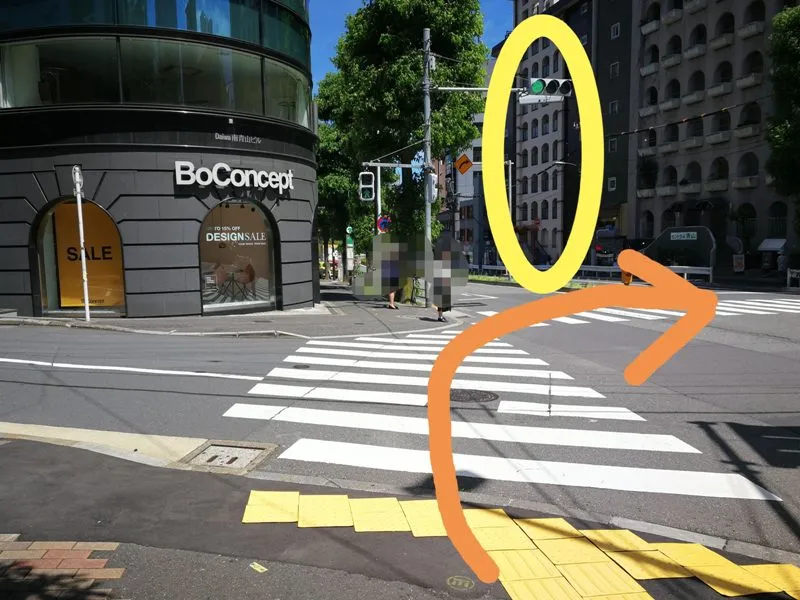 BoConcept前の交差点と、当院が入るビルを黄色マークで示した写真（オレンジ矢印付き）