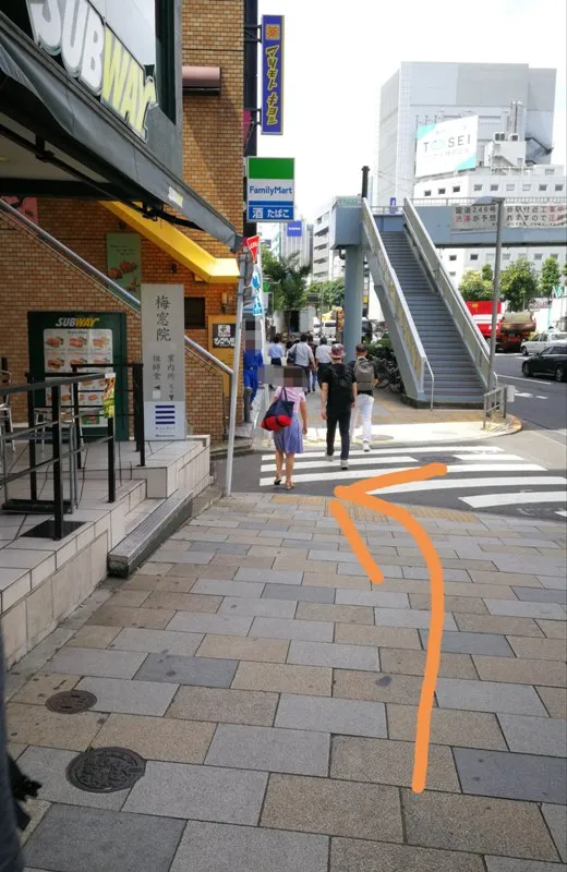 外苑前駅1a出口からファミリーマート前の細道へ曲がる方向を示した写真（オレンジ矢印付き）