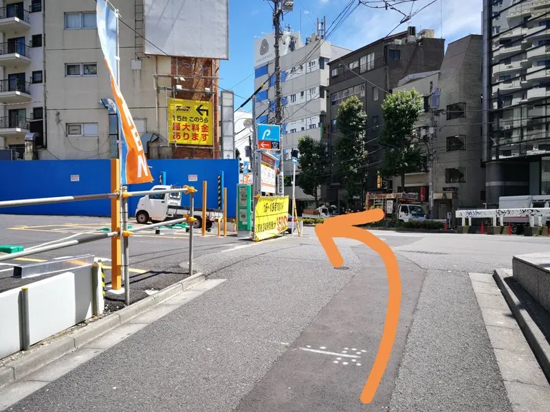 細道を抜けて大通りに出た場所で左に曲がる方向を示した写真（オレンジ矢印付き）