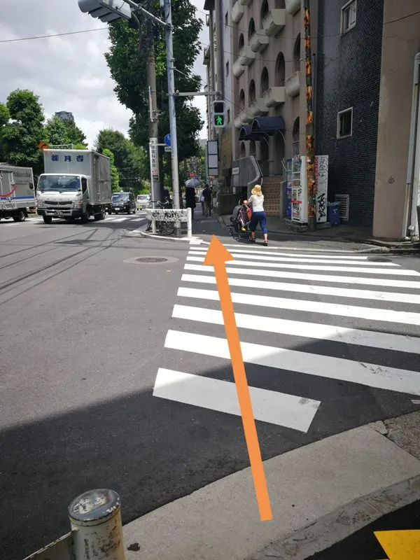 最初の交差点を渡って直進する方向を示した写真（オレンジ矢印付き）