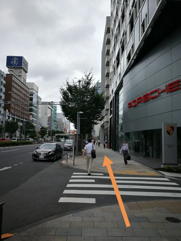 青山通り沿いのポルシェ店舗前を通る様子（オレンジ矢印付き）
