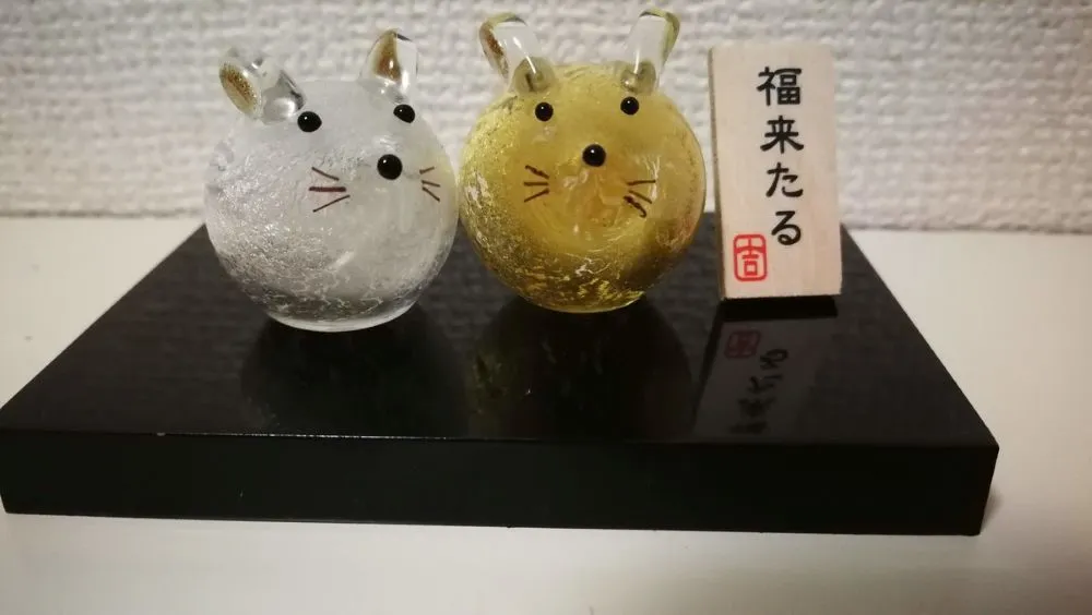 靴棚に置かれた「福来たる」と書かれた木製看板と、透明な白と黄色のネズミの飾り。