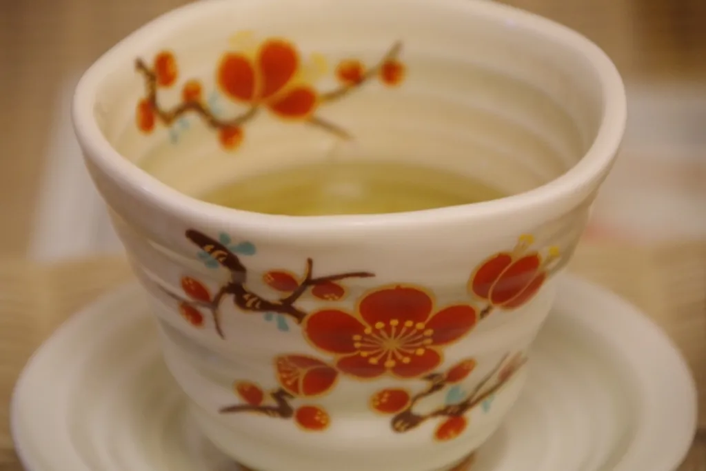 梅の花が描かれた陶器の茶碗に入った漢方茶。